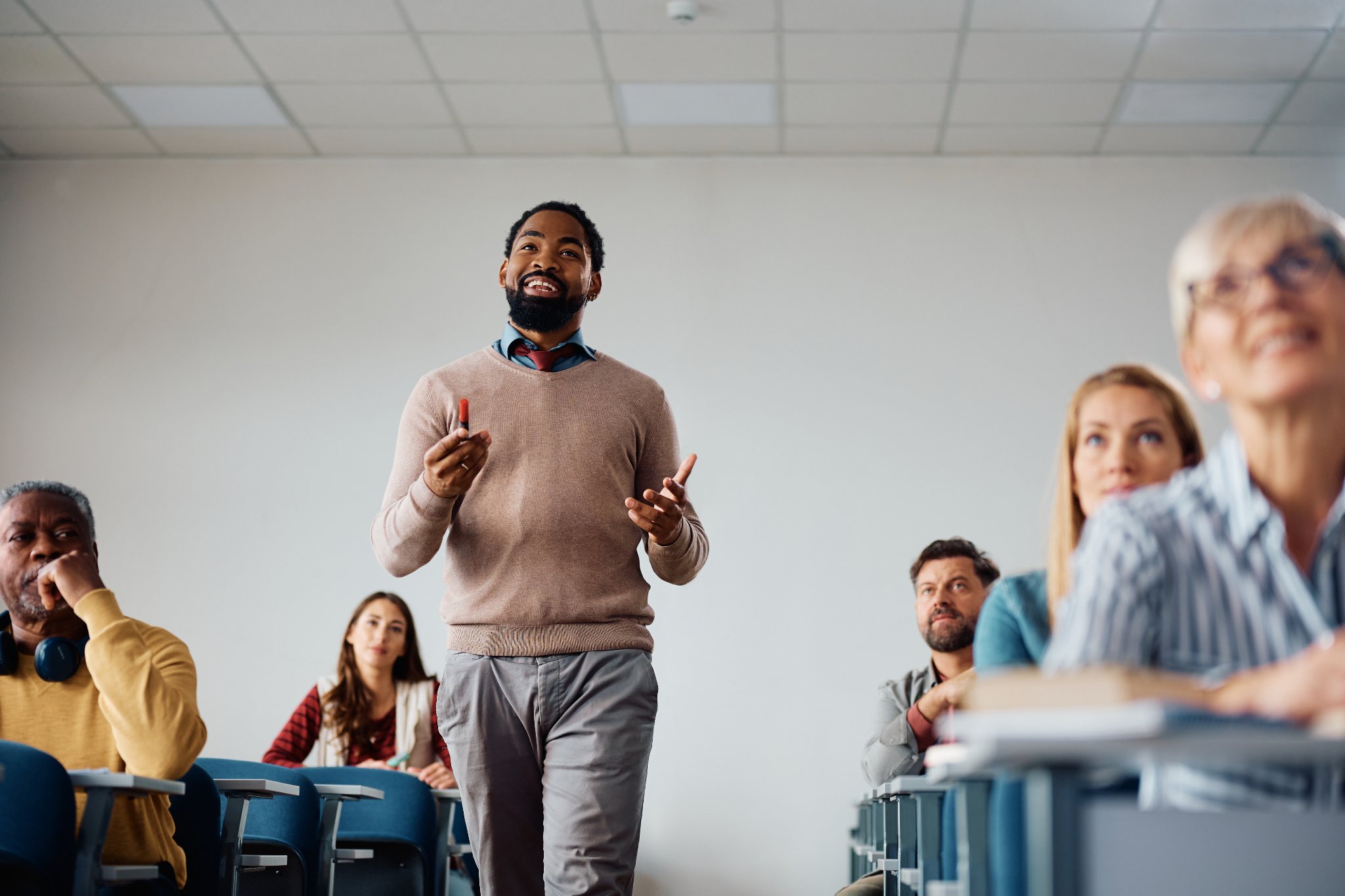 Young Black professor guest lecturing to a diverse classroom audience